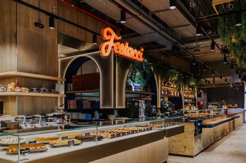 Front-of-house interior at Festacci restaurant, Malta, showing banquette seating, food counter, and neon signage