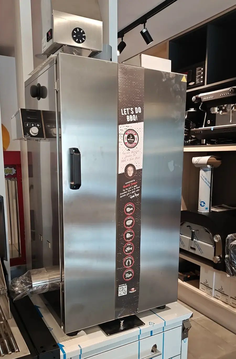 Borniak stainless steel electric smoker cabinet displayed in the Spiteri Catering showroom, with Let's Do BBQ branding visible on the front panel