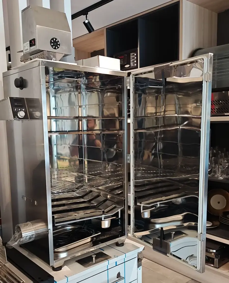 Borniak electric smoker shown with doors open, revealing multiple adjustable racks and drip trays inside the stainless steel cooking chamber