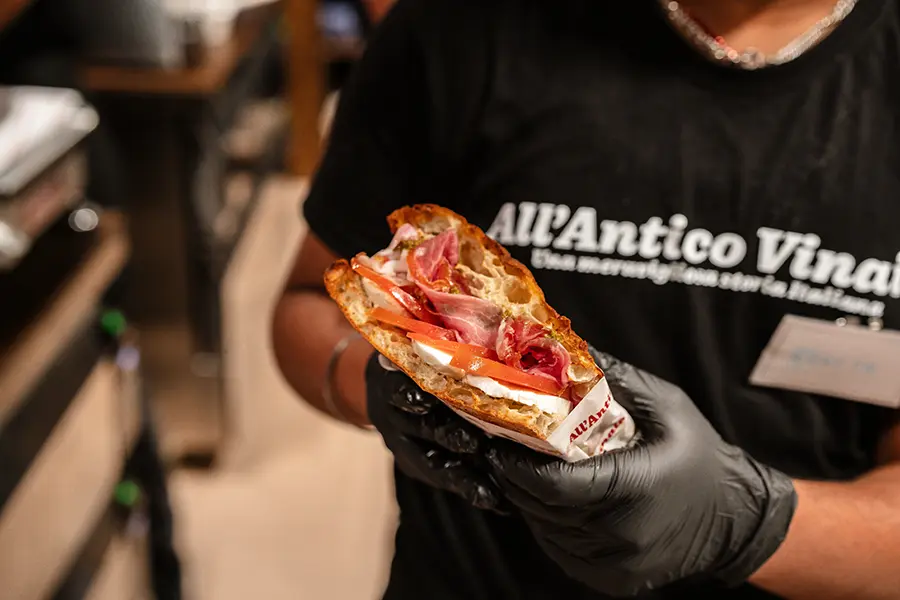 Freshly baked schiacciata resting on a white chopping board beside a Berkel slicer at All'Antico Vinaio Valletta