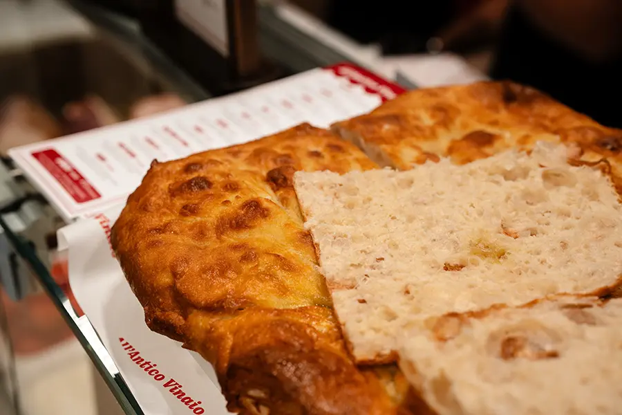 Sliced schiacciata on display at the All'Antico Vinaio Valletta counter, showing the open crumb and golden crust