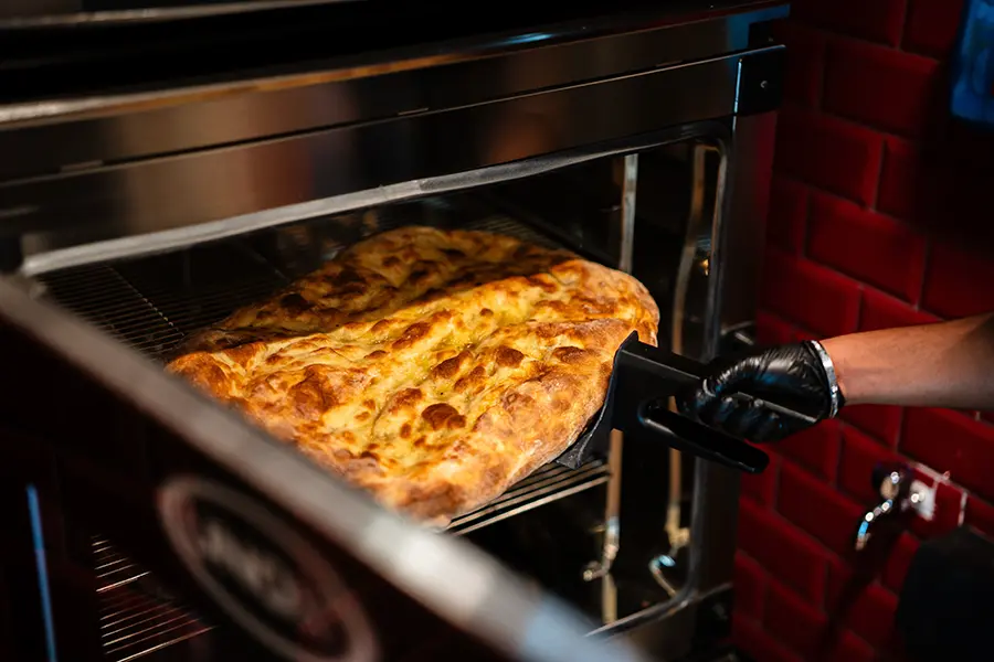 Schiacciata being removed from a Unox CHEFTOP oven by a team member wearing black gloves at All'Antico Vinaio Valletta