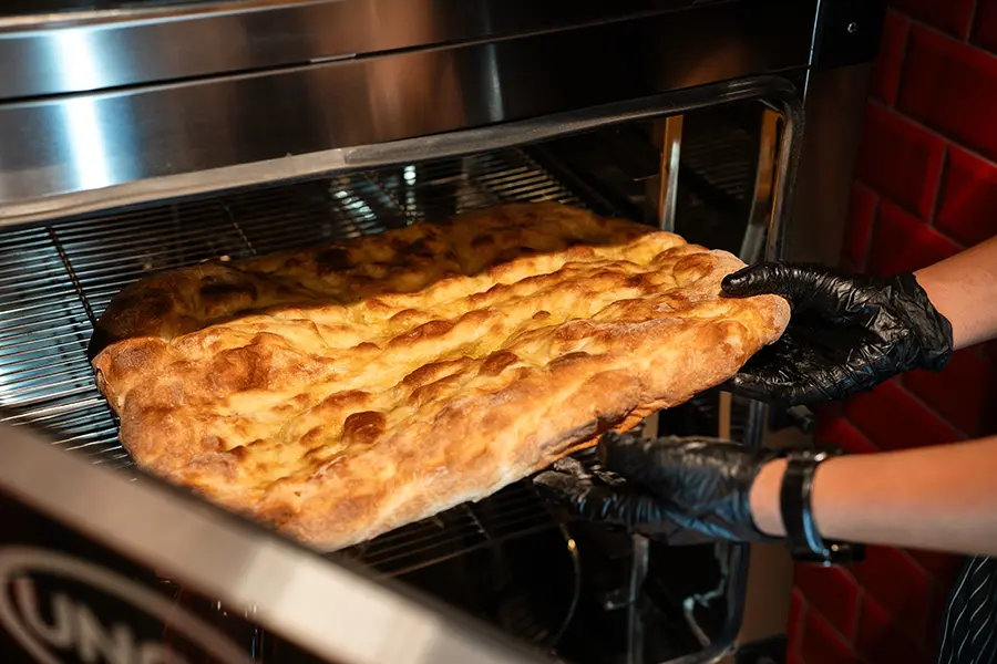 Schiacciata flatbread being drawn from a Unox CHEFTOP oven, showing a well-coloured blistered crust