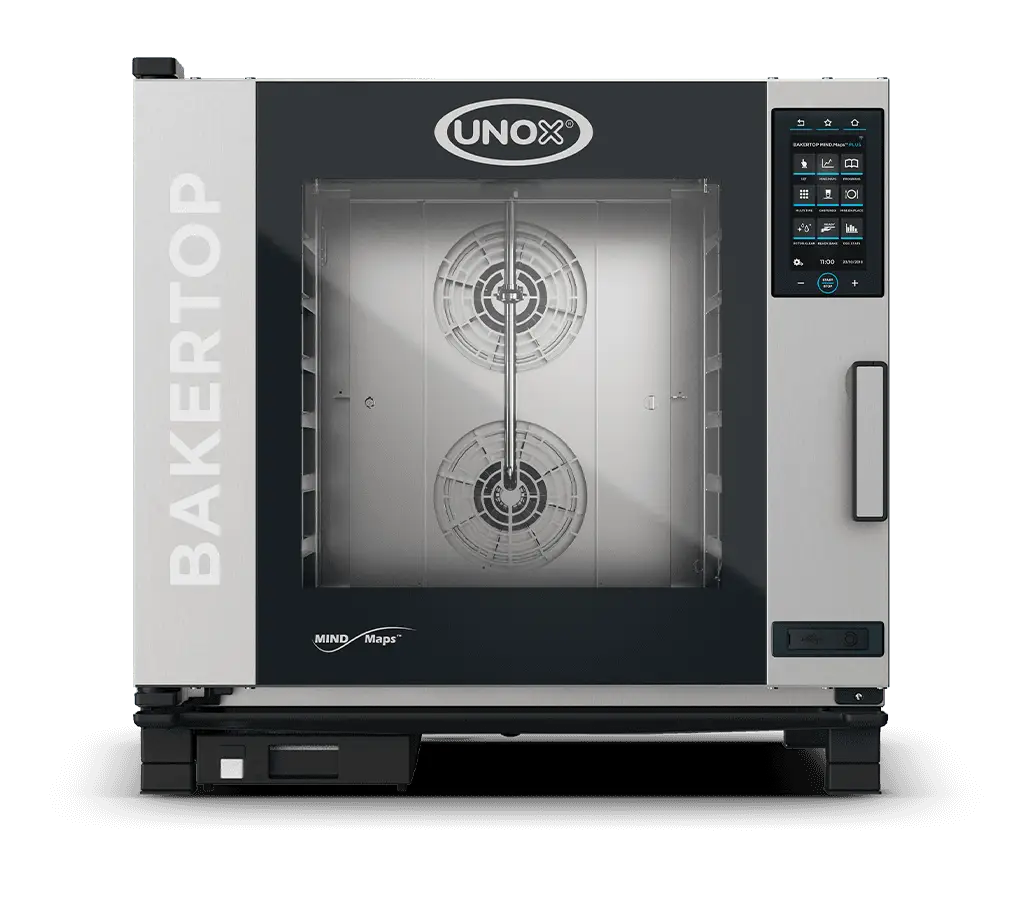 A pastry chef in a beige apron opening the door of a Unox BAKERTOP MIND.Maps oven in a professional kitchen