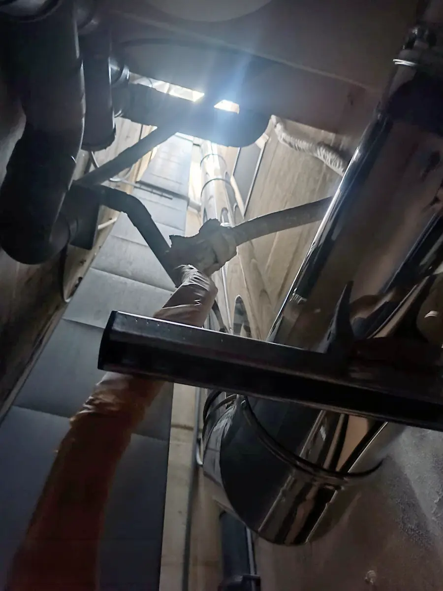 Close-up of tightly jointed stainless steel flue sections passing through the interior of the building at Joe's Street Pizza, with a gas cylinder visible