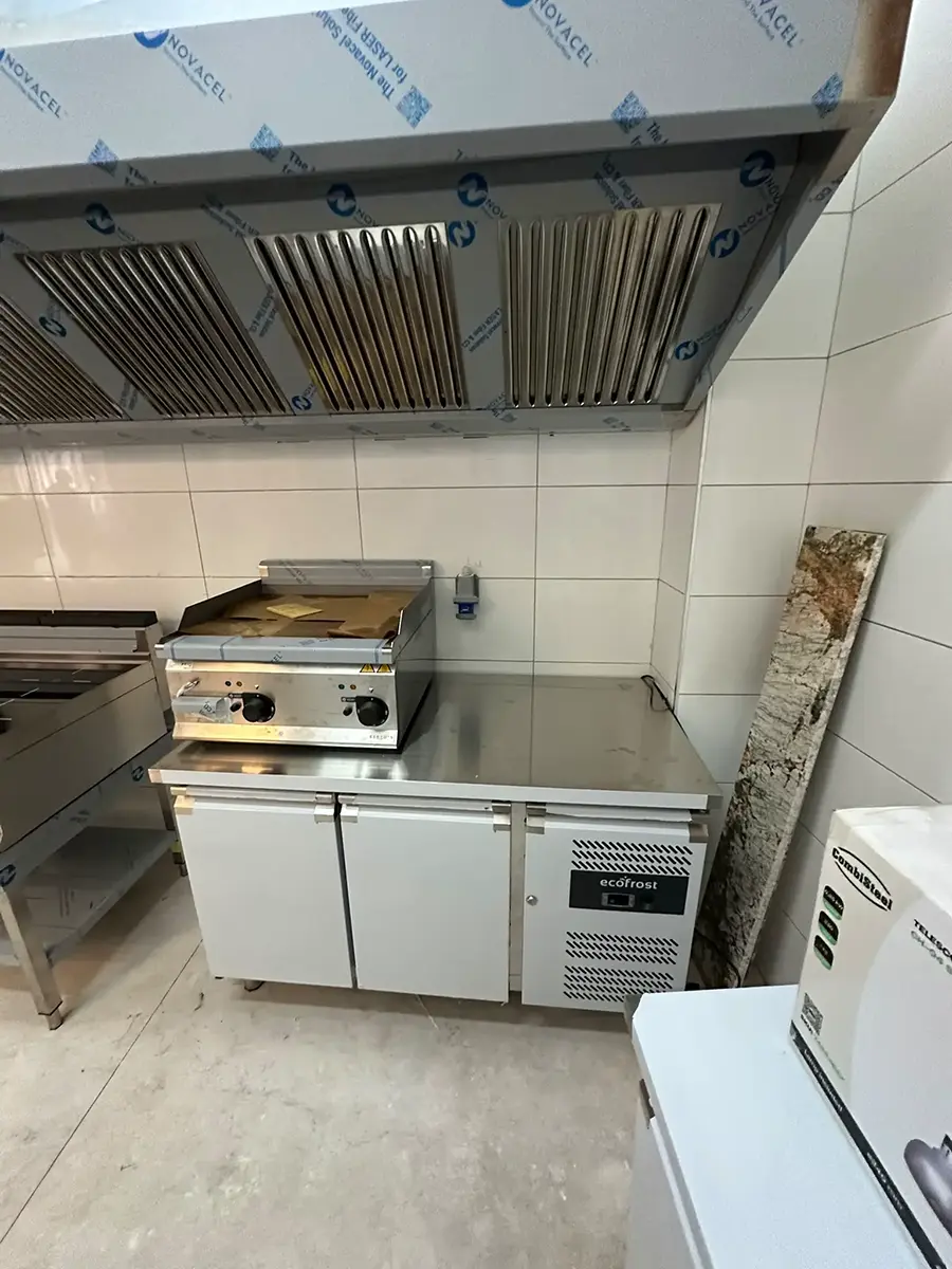 Commercial kitchen installation in Naxxar, Malta, showing Combisteel extraction canopy, cooking line, and upright refrigerator during fit-out